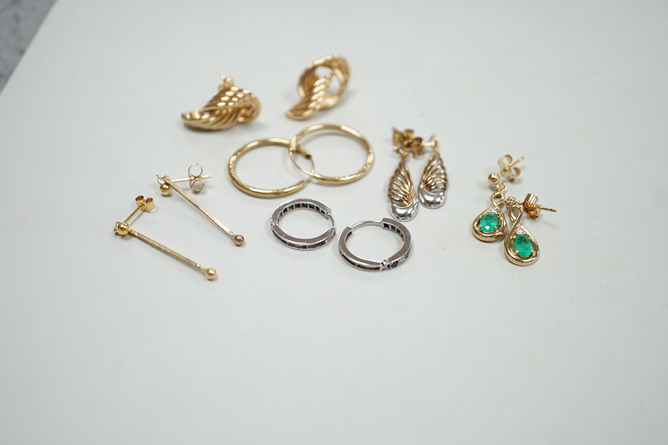 Two modern pairs of 375 earrings, a pair of 9ct, emerald and diamond set drop earrings and a pair of 9ct white gold, sapphire and diamond chip set loop earrings, gross weight 9.2 grams and two pairs of yellow metal earri